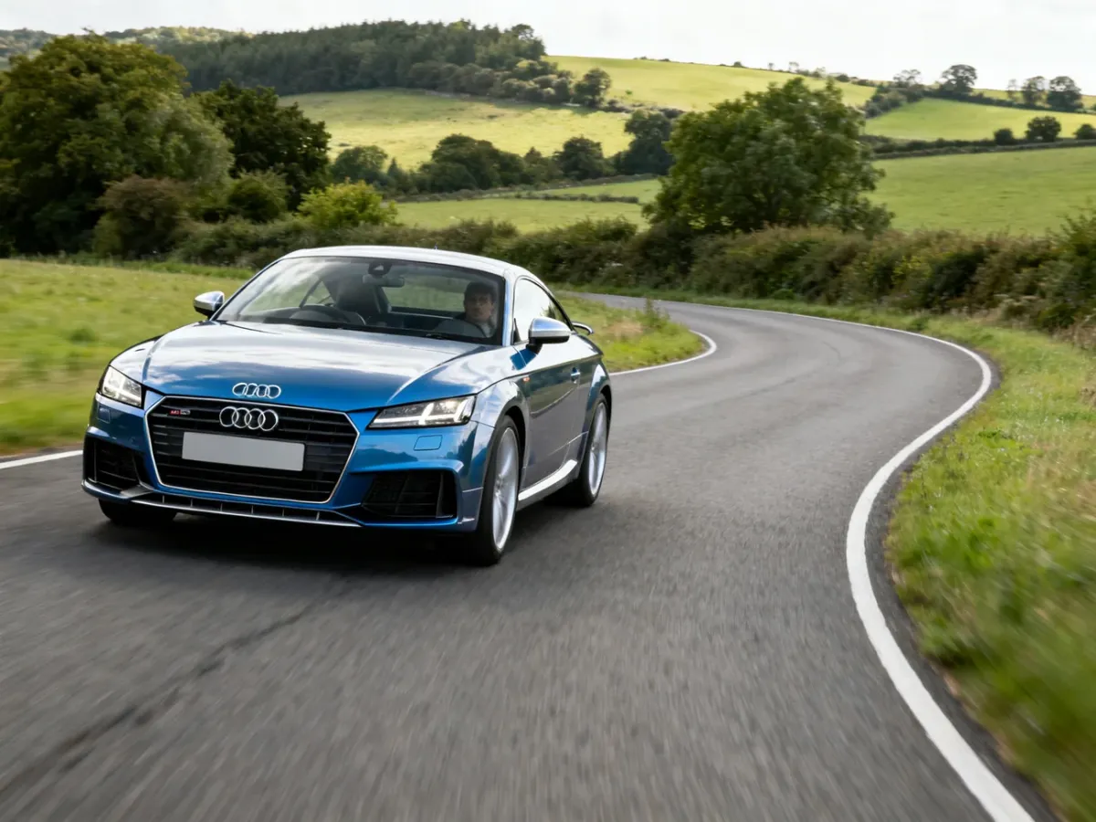 Audi TT coupe jadące dynamicznie po malowniczej drodze pozamiejskiej