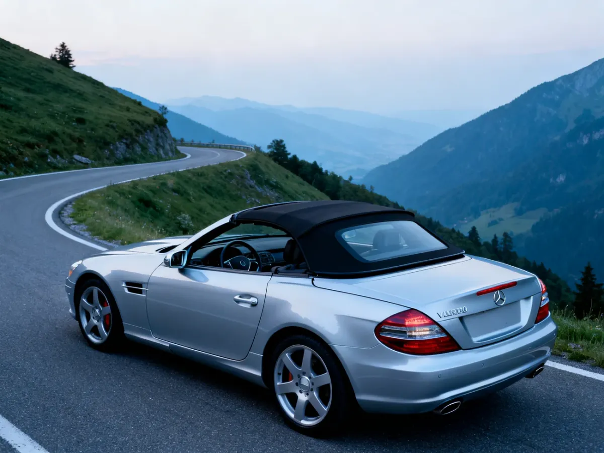 Srebrny Mercedes SLK na górskiej drodze z częściowo otwartym twardym dachem