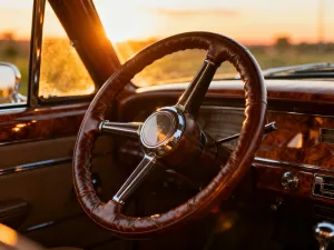 Srebrny sedan Mercedes-Benz zaparkowany na nowoczesnym podjeździe w świetle zachodzącego słońca.
